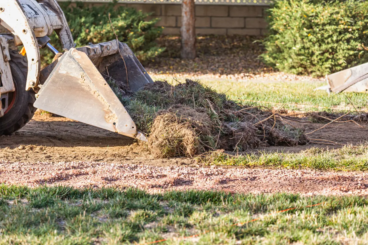 Equipment scooping grass and soil during yard cleanup